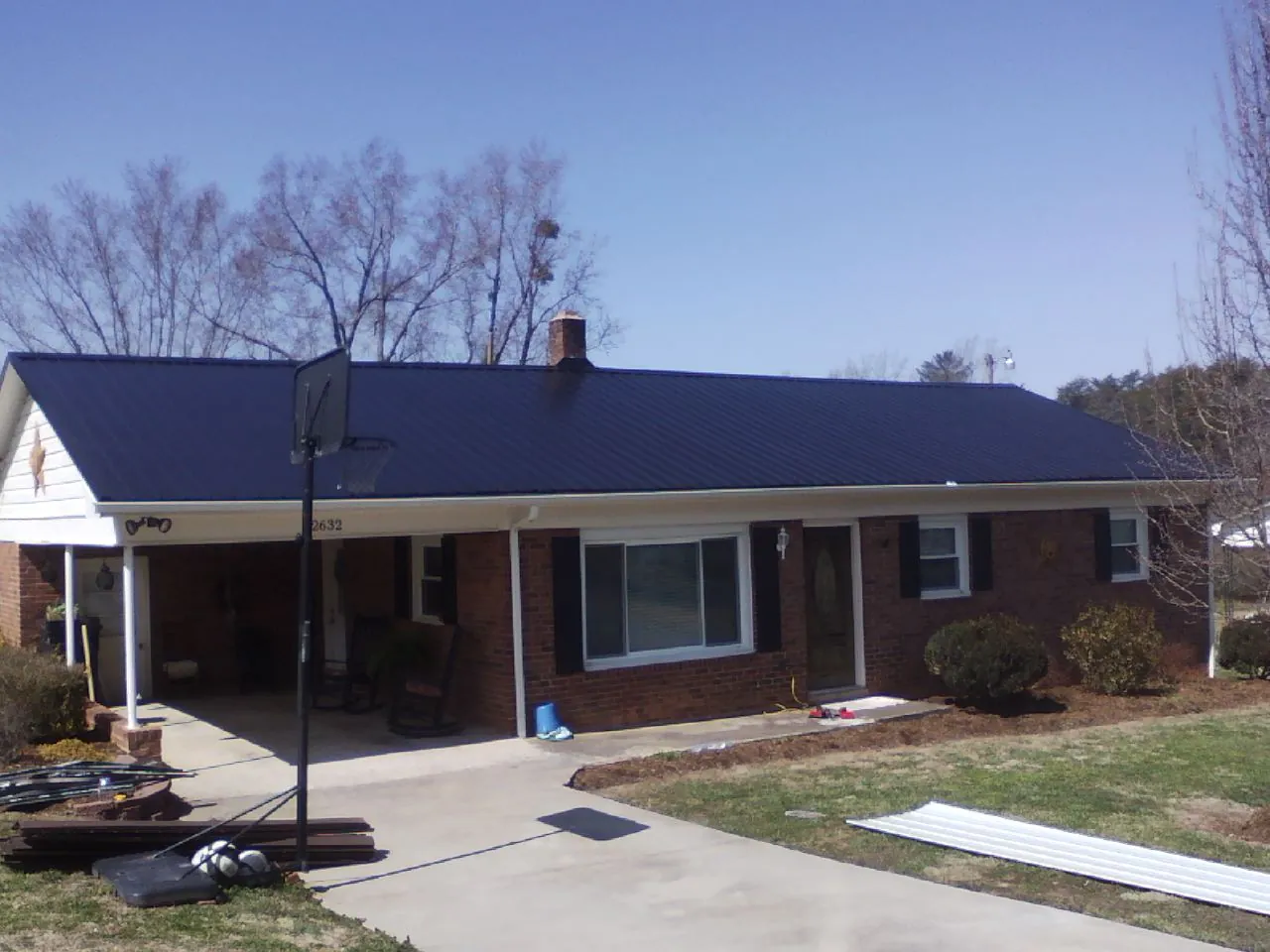 Finished dark blue metal roof on a brick ranch with a carport in Monmouth