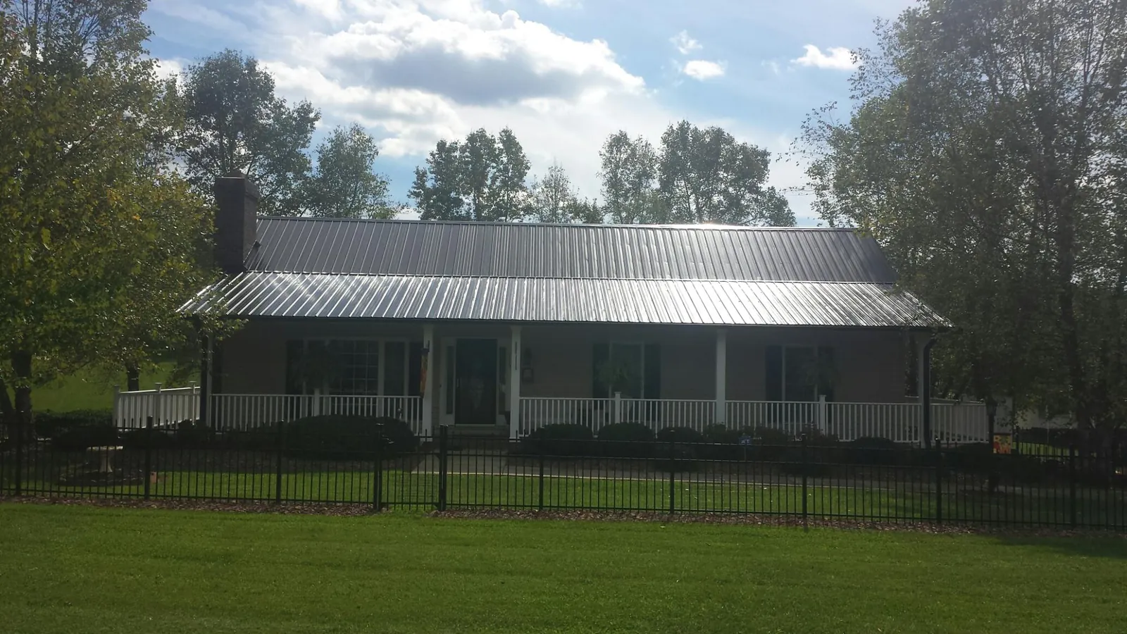 Gray metal roof on a brick ranch with a full width front porch — Gutter Guard Installation work by our crew in Monmouth