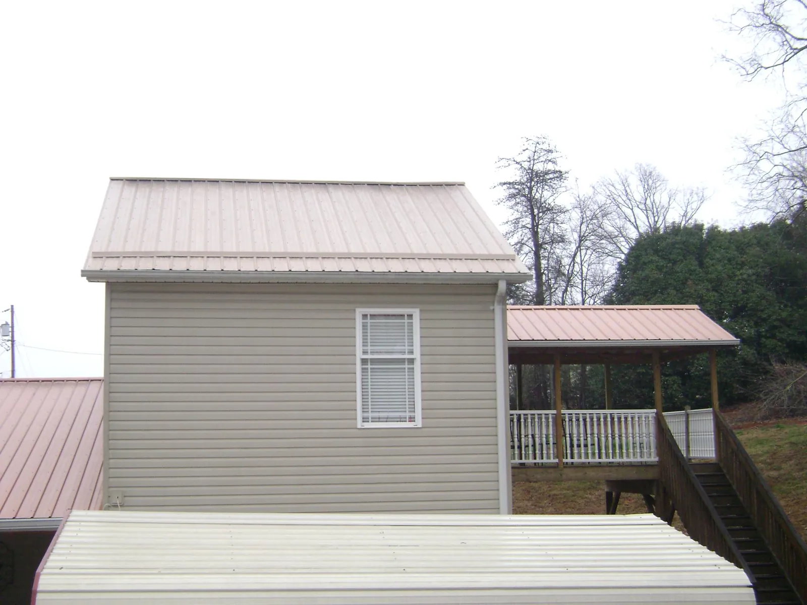 Tan metal roofs on a two story addition and attached porch, from a Roof Replacement job in Monmouth