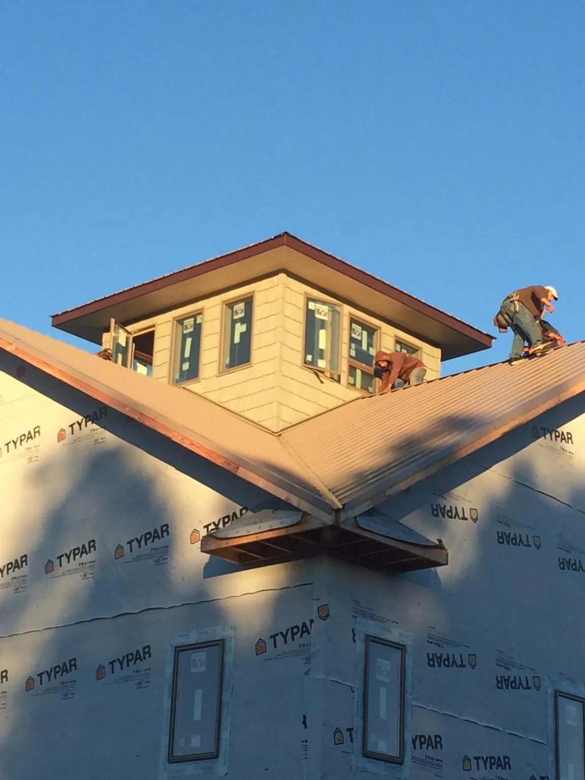 Roofers working around a rooftop cupola on a new metal roof at sunset — Roof Waterproofing in Monmouth by Roofing Brothers